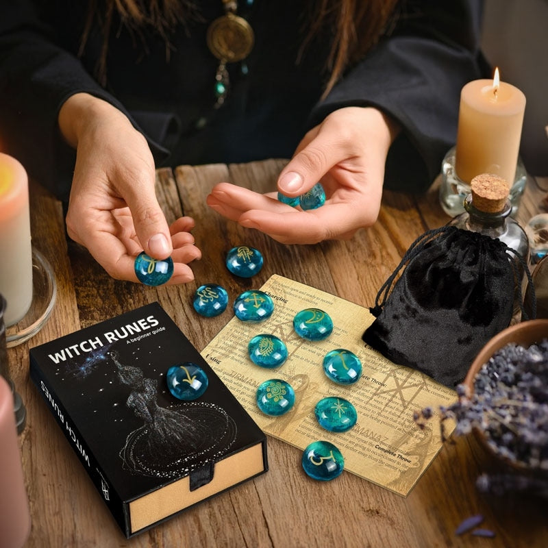 Person holding blue runes next to a book titled 'Witch Runes' on a wooden table.