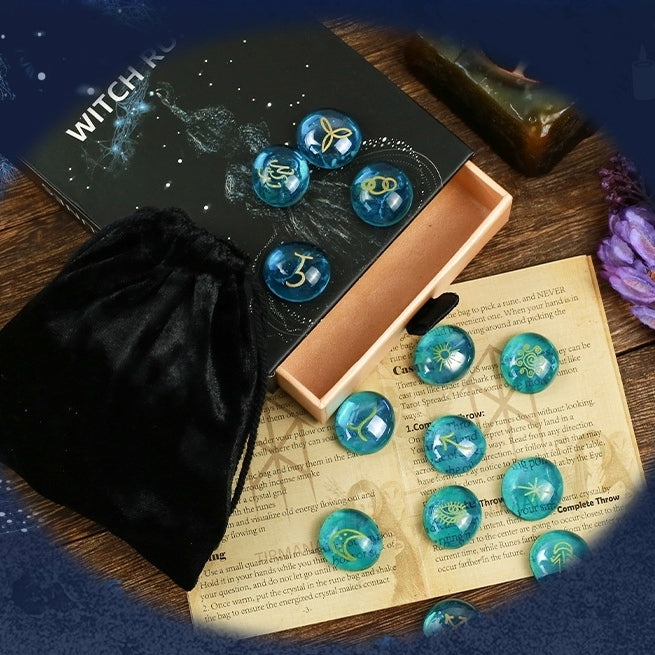 Set of blue crystal witch stones with star signs on a wooden surface with a black pouch and book.