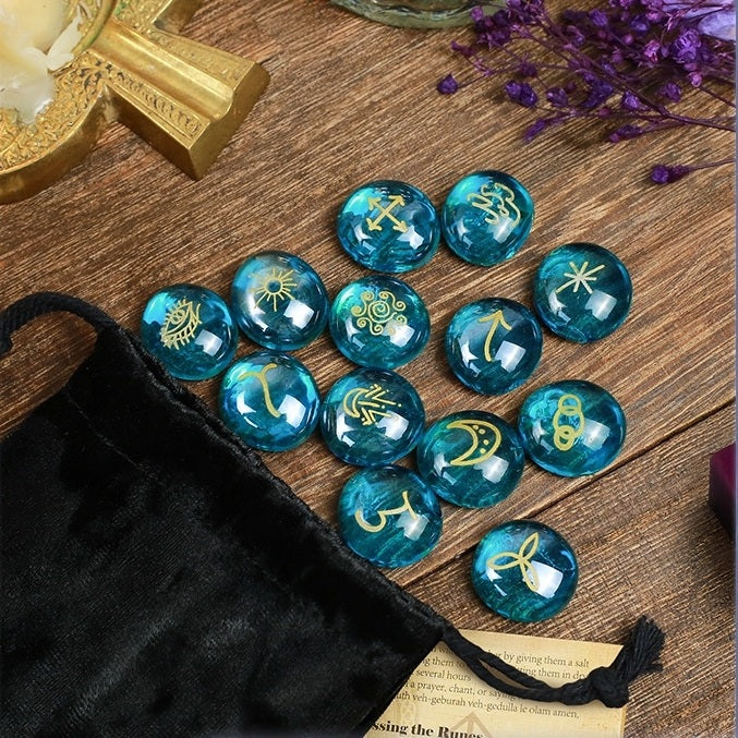 Blue glass witch stones with star patterns on a wooden surface next to a black drawstring bag.