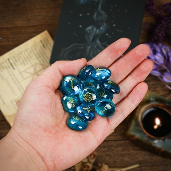 Hand holding blue crystal witch stone with symbols on a wooden surface