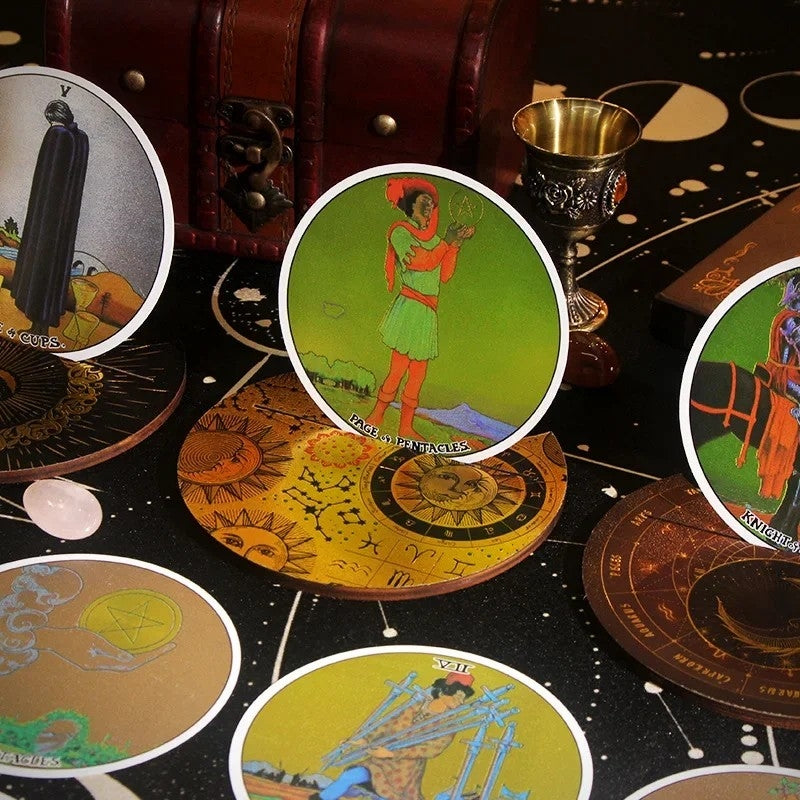 Collection of Circular Gold Foil tarot cards on a dark surface with a wooden chest and other tarot paraphernalia.