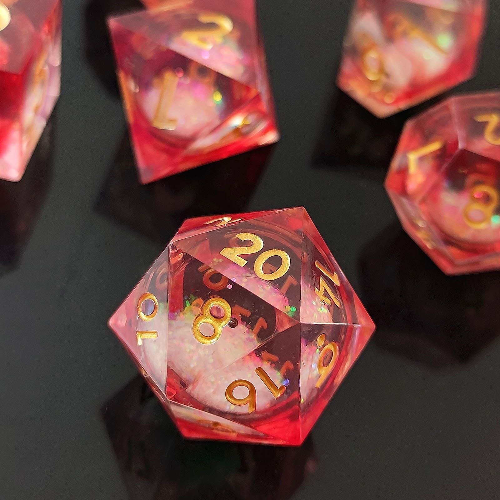Red resin liquid core dice with gold foil numbers on a black background