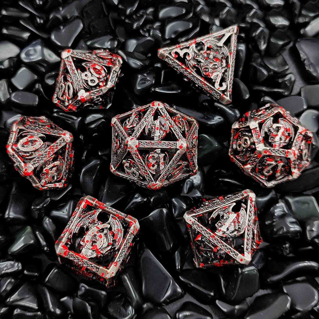 Set of red and silver polyhedral Hollow Metal dice on black pebbles
