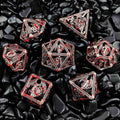 Set of red and silver polyhedral Hollow Metal dice on black pebbles