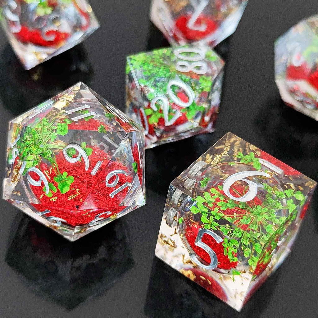 Set of botanical resin liquid sand core dice with red and green numbers on a reflective black surface