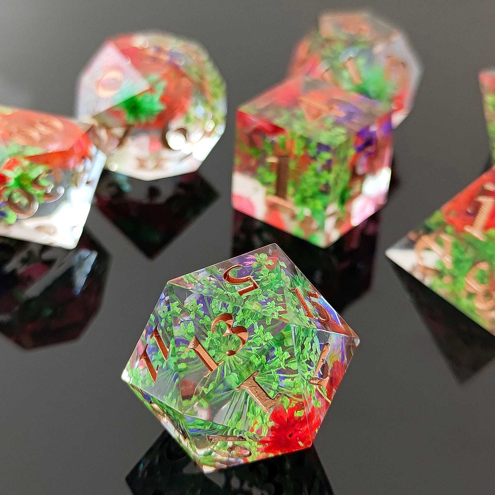 Colorful botanical resin polyhedral dice set on a reflective black surface