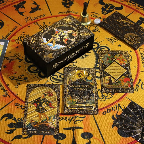 Gold foil tarot cards with decorative box on a zodiac-themed fabric background