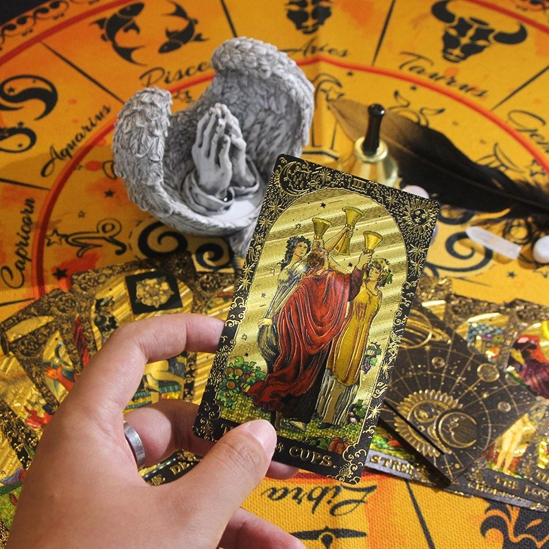 Hand holding a tarot card over a tarot spread with astrological symbols