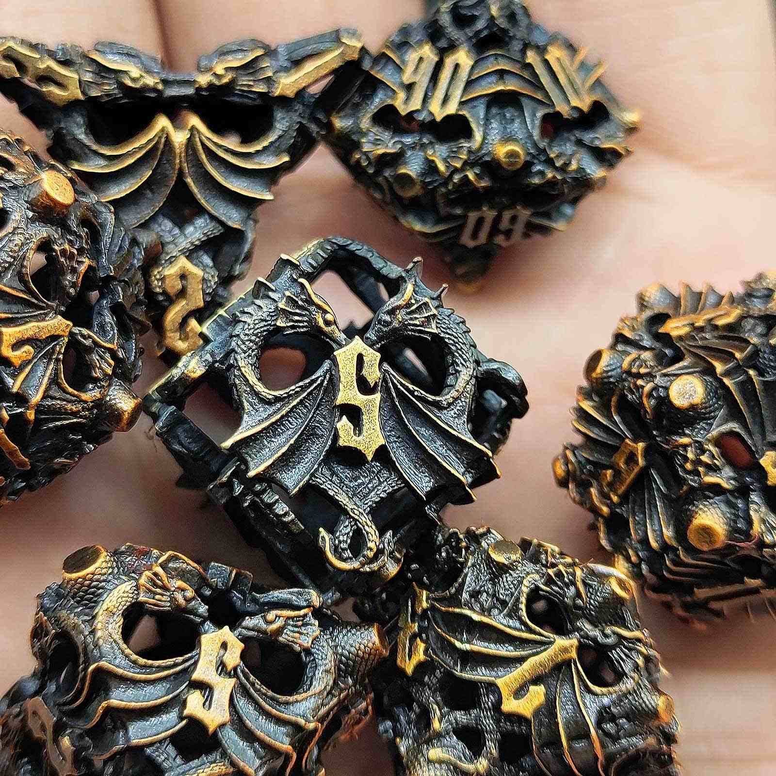 Close-up of metal dragon-shaped Hollow Metal D&D Dice with gold accents.