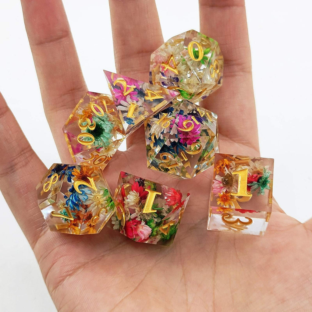 Colorful Sharp Edge Polyhedral resin dice with floral designs held in a hand against a white background
