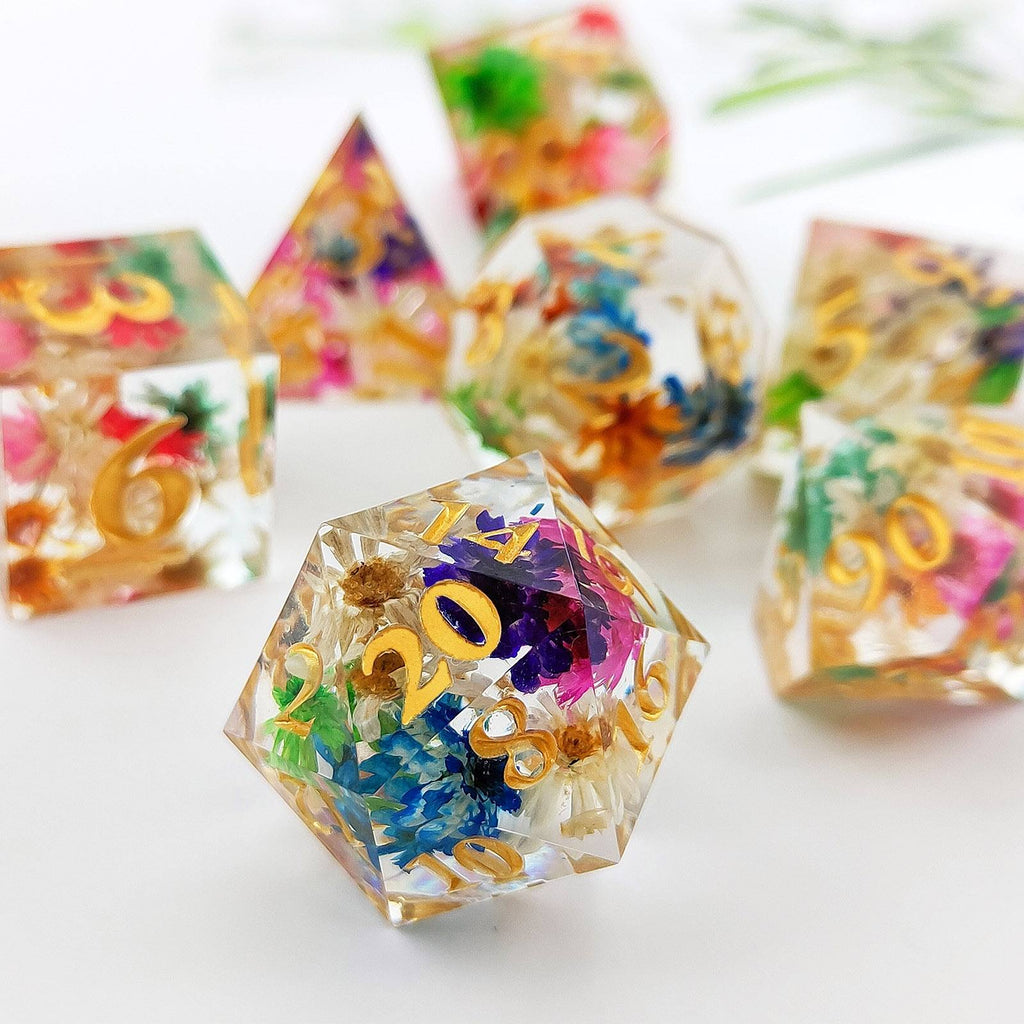 Colorful polyhedral resin dice set wirh flower design on a white background