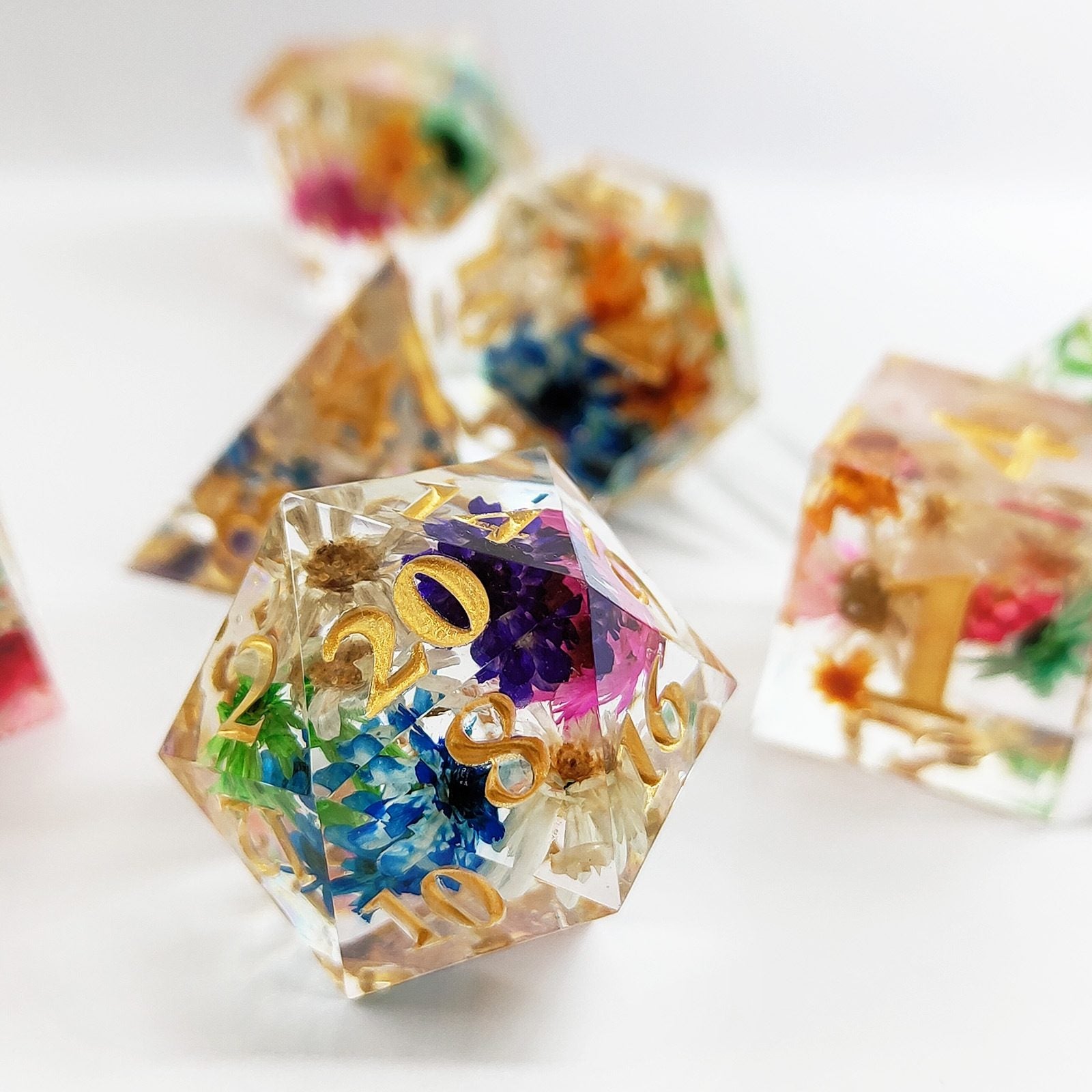 Translucent Sharp Edge Polyhedral resin dice with embedded flowers and gold numbers on a white background