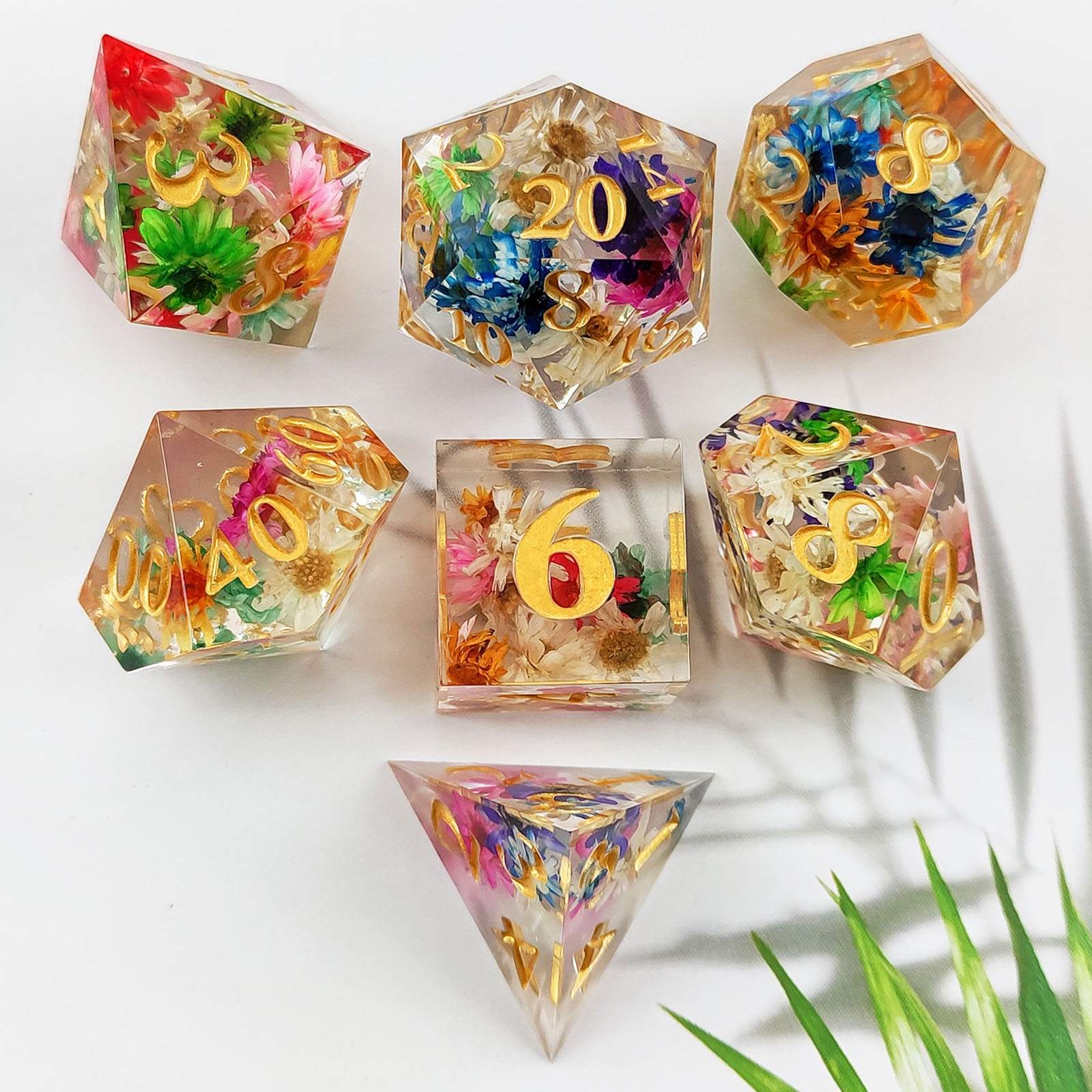 Sharp Edge Polyhedral resin dice with floral and gold number designs on a white background