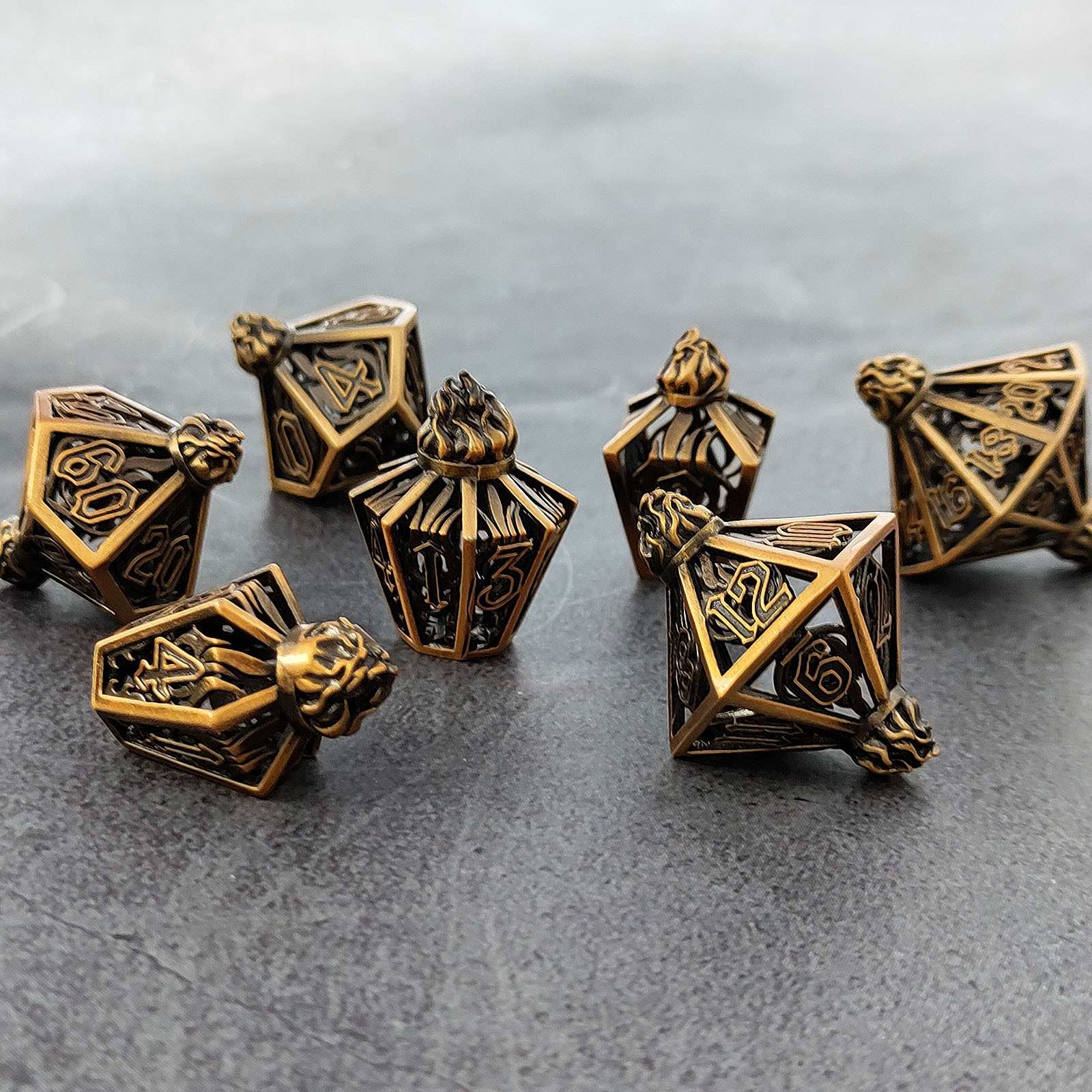 Set of bronze polyhedral lantern shaped metal hollow dice on a gray surface