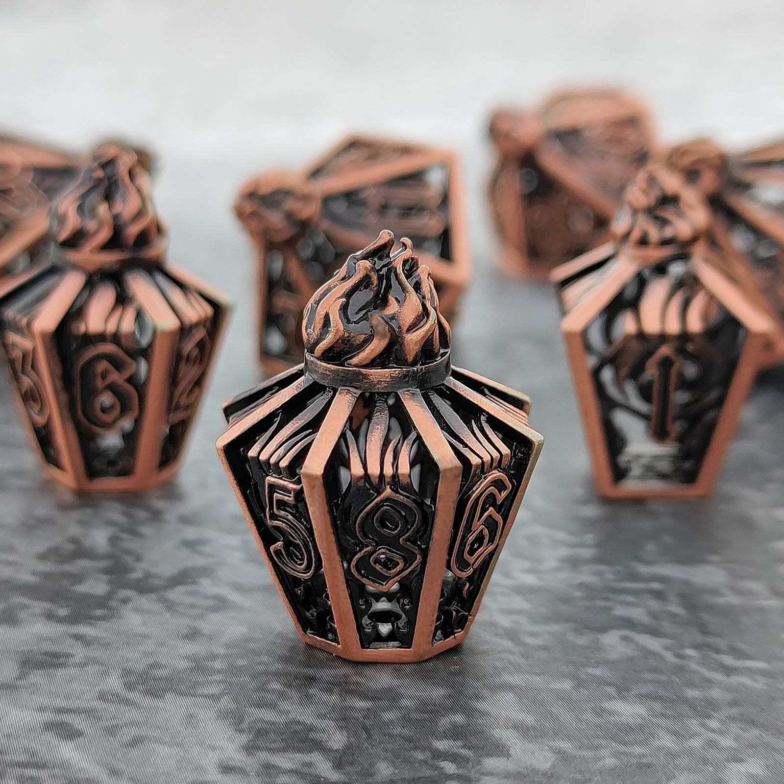 copper lantern-like hollow metal dice with intricate designs on a gray surface