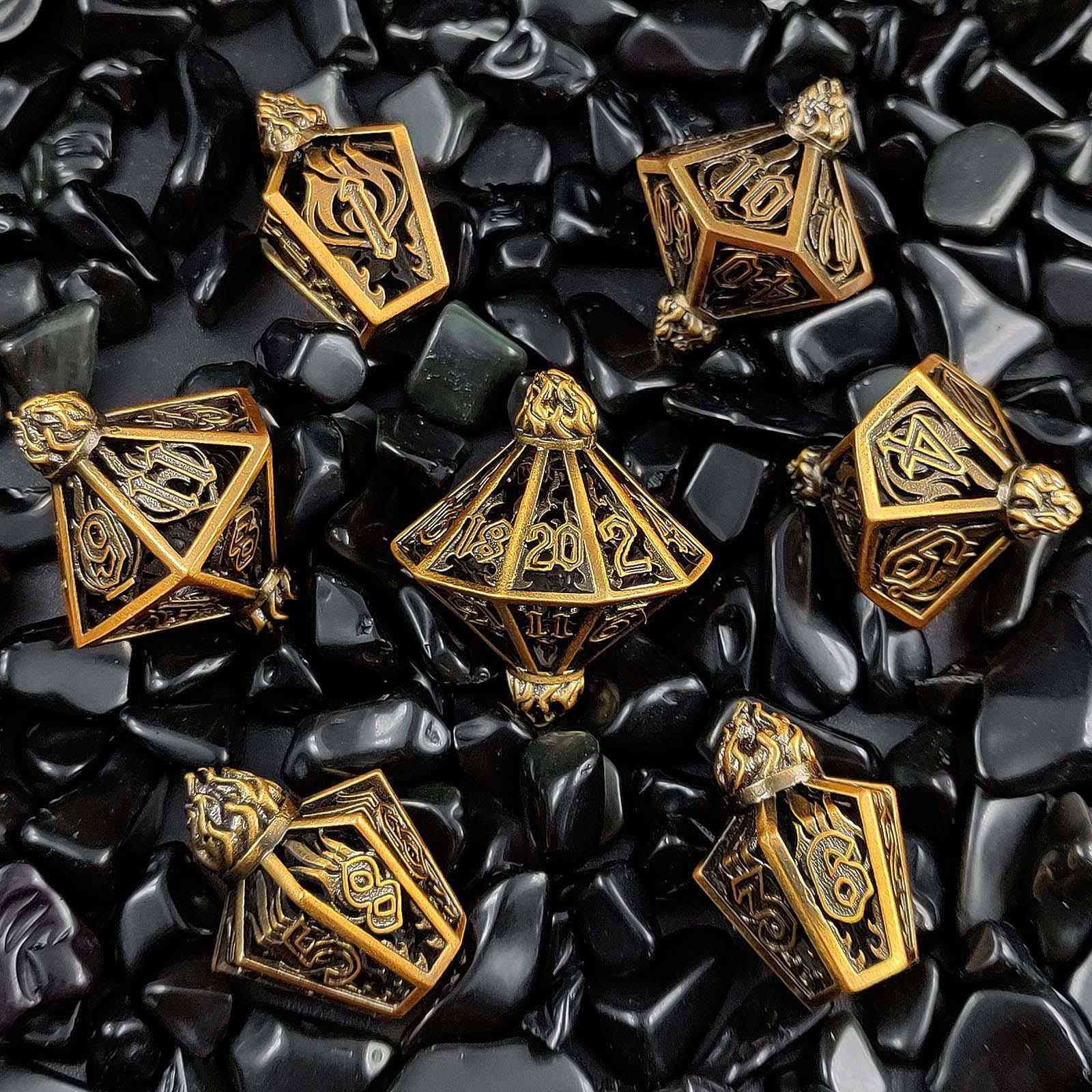 Gold lantern shaped metal hollow polyhedral dice set on black stone surface