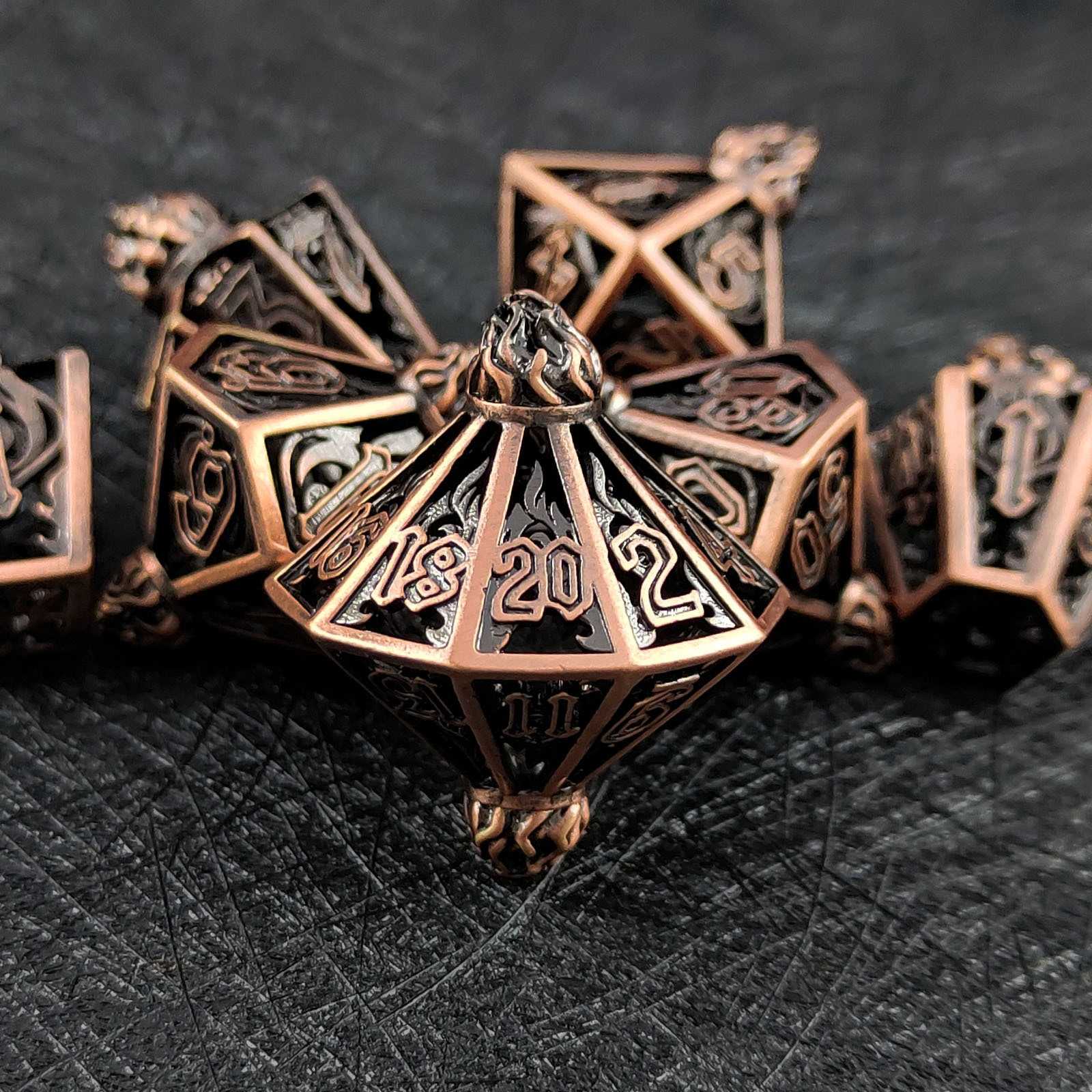 Set of bronze polyhedral hollow dice on a dark textured surface