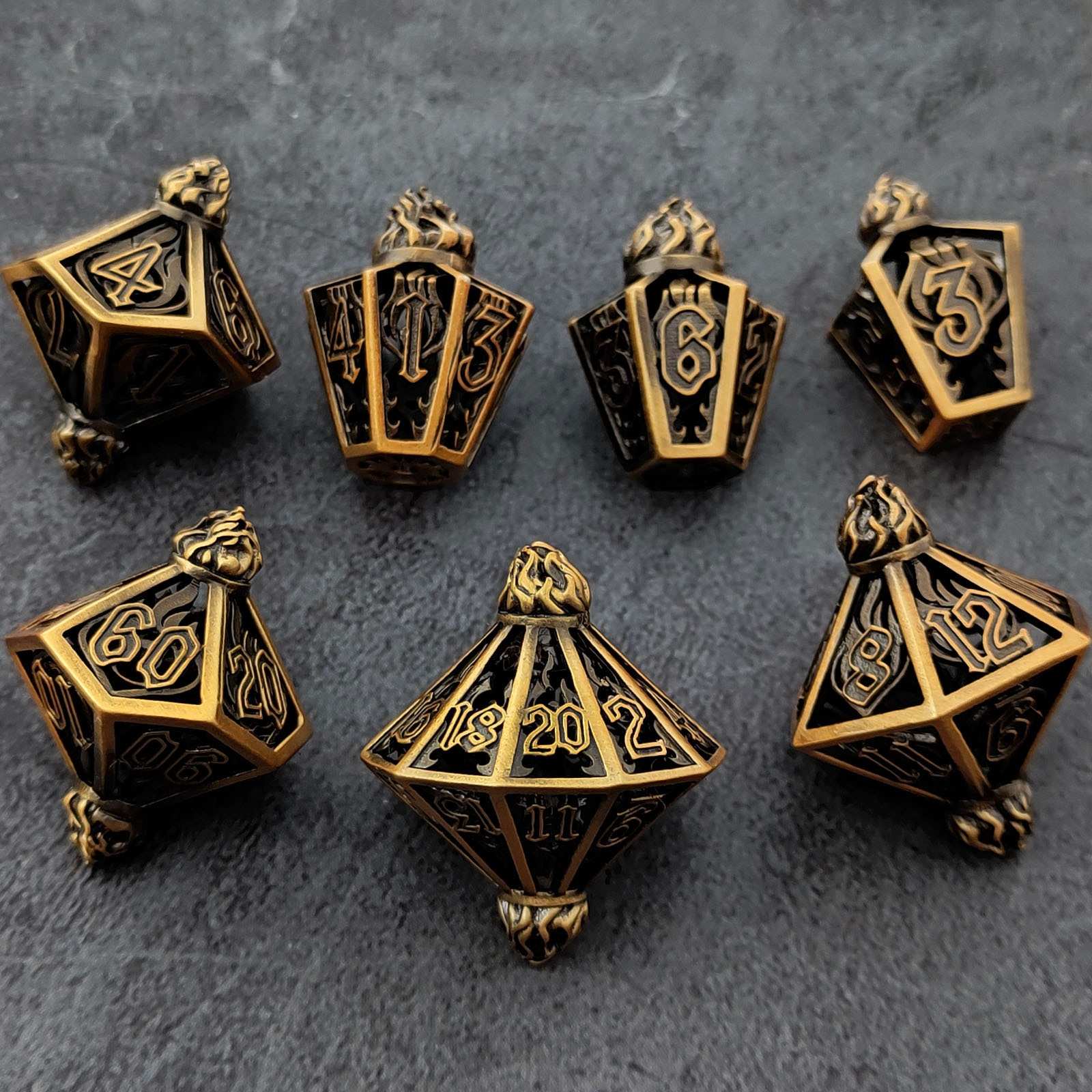 Set of ornate gold and black polyhedral lantern shaped metal hollow dice on a dark surface