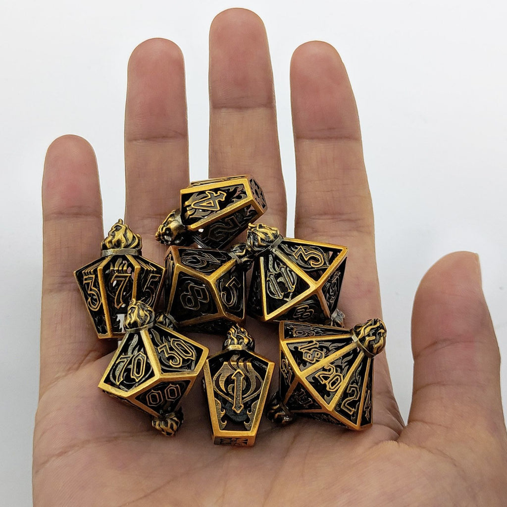 Gold and black polyhedral metal holow dice set held in a hand against a white background