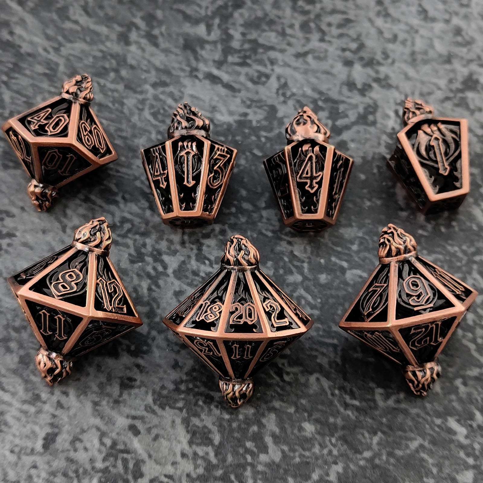 Set of bronze polyhedral dice with black numbering on a textured gray background