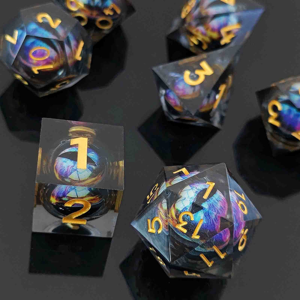 Set of colorful liquid core dice with gold numbers on a reflective black surface