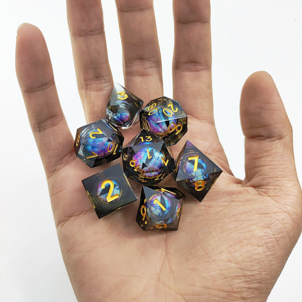 Set of colorful liquid core resin dice held in a hand against a white background
