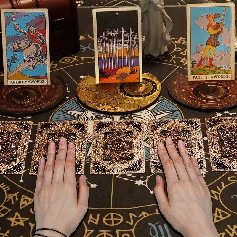 Gold Foil Tarot cards on a mystical table with hands hovering over them