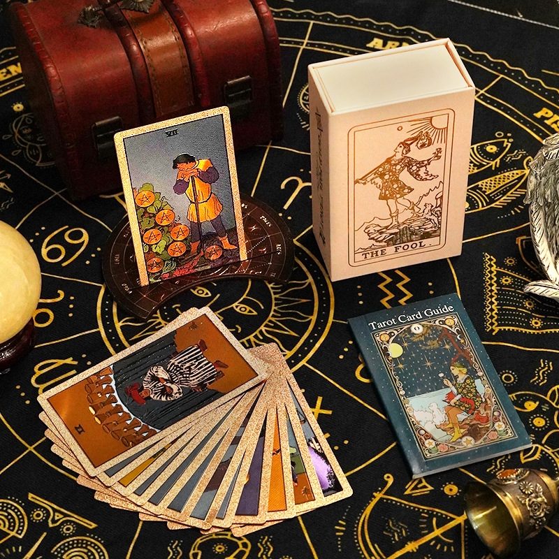 Collection of Gold Foil tarot cards on an astrological table with a wooden box labeled 'The Fool'.