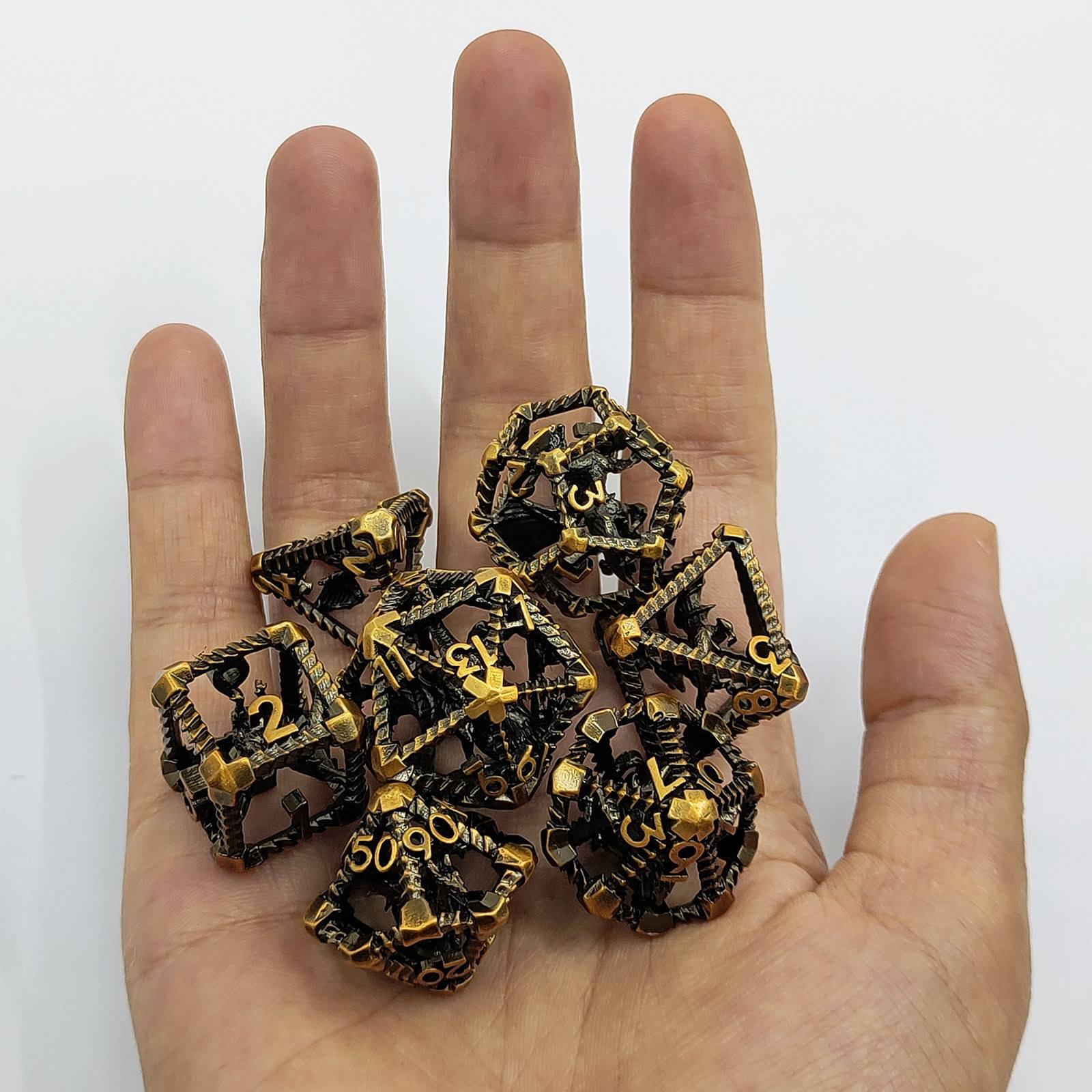 Hand holding Copper Polyhedral RPG dices with gold and bronze finish on a white background
