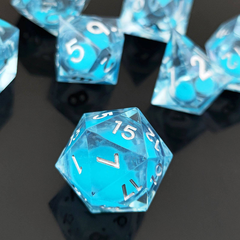 Blue polyhedral Glow-in-the-Dark Liquid Core dice with white numbers on a reflective black surface