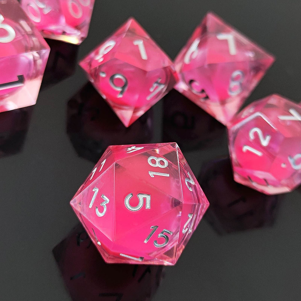 Pink polyhedral Glow-in-the-Dark Liquid Core dice set on a reflective black surface