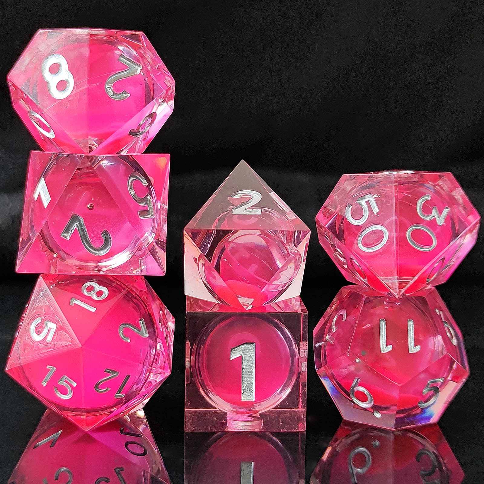Set of pink polyhedral Glow-in-the-Dark Liquid Core dice with silver numbers on a black background