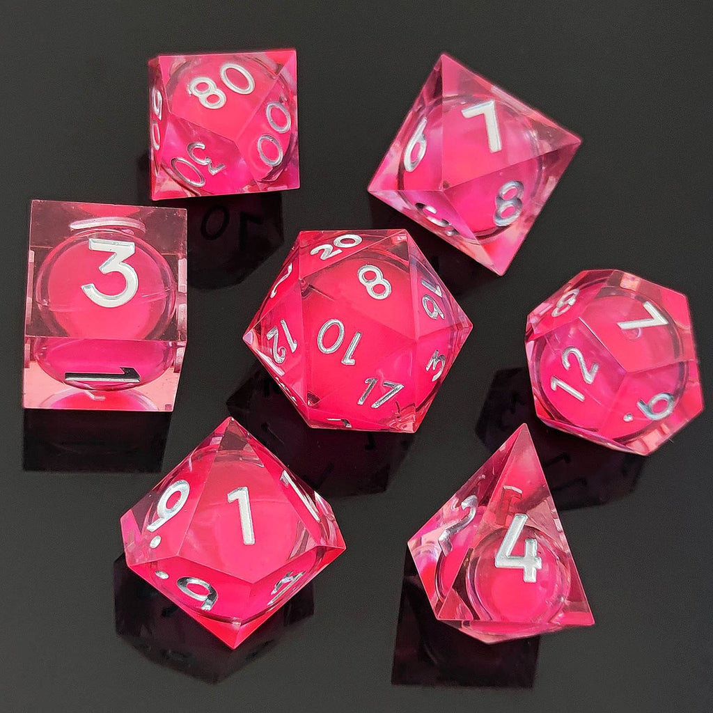 Set of pink transparent polyhedral Glow-in-the-Dark Liquid Core dice on a black background