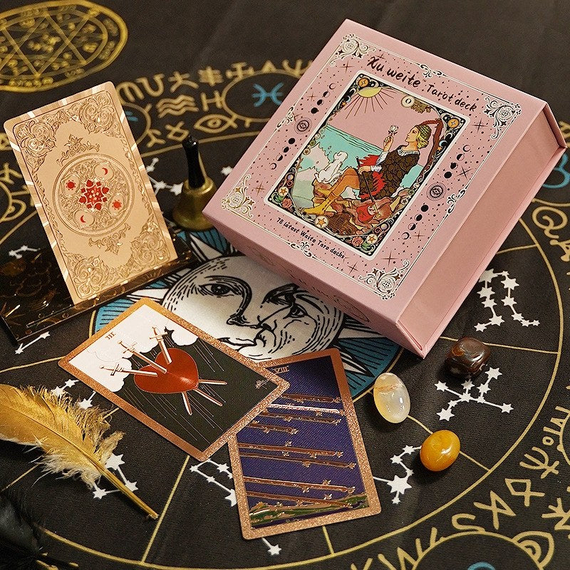 Pink foil tarot card box with tarot cards and Chakra crystals on a black astrological circle
