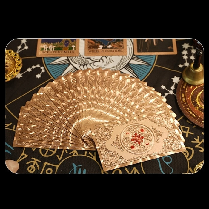 Gold foil taro cards fanned out on a tarot card background with symbols and text.