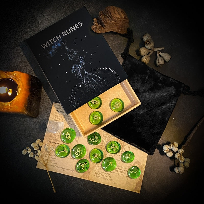 Witch runes set with green stones on a dark surface with candles and herbs.