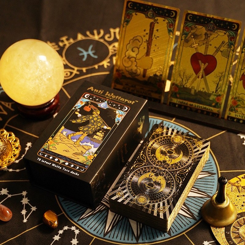 premium gold foil Tarot cards with a crystal ball and other paraphernalia on a tarot board