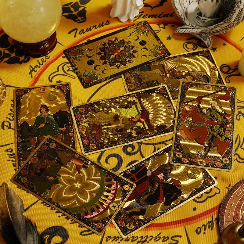 Collection of Kaleidoscope Holographic Rainbow Foil tarot cards on a yellow cloth with astrological symbols