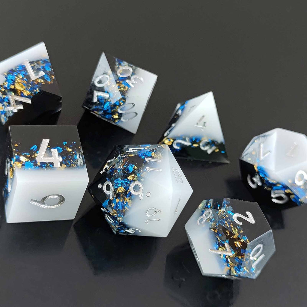 Set of Liquid Core Resin dice with blue and gold glitter on a black background