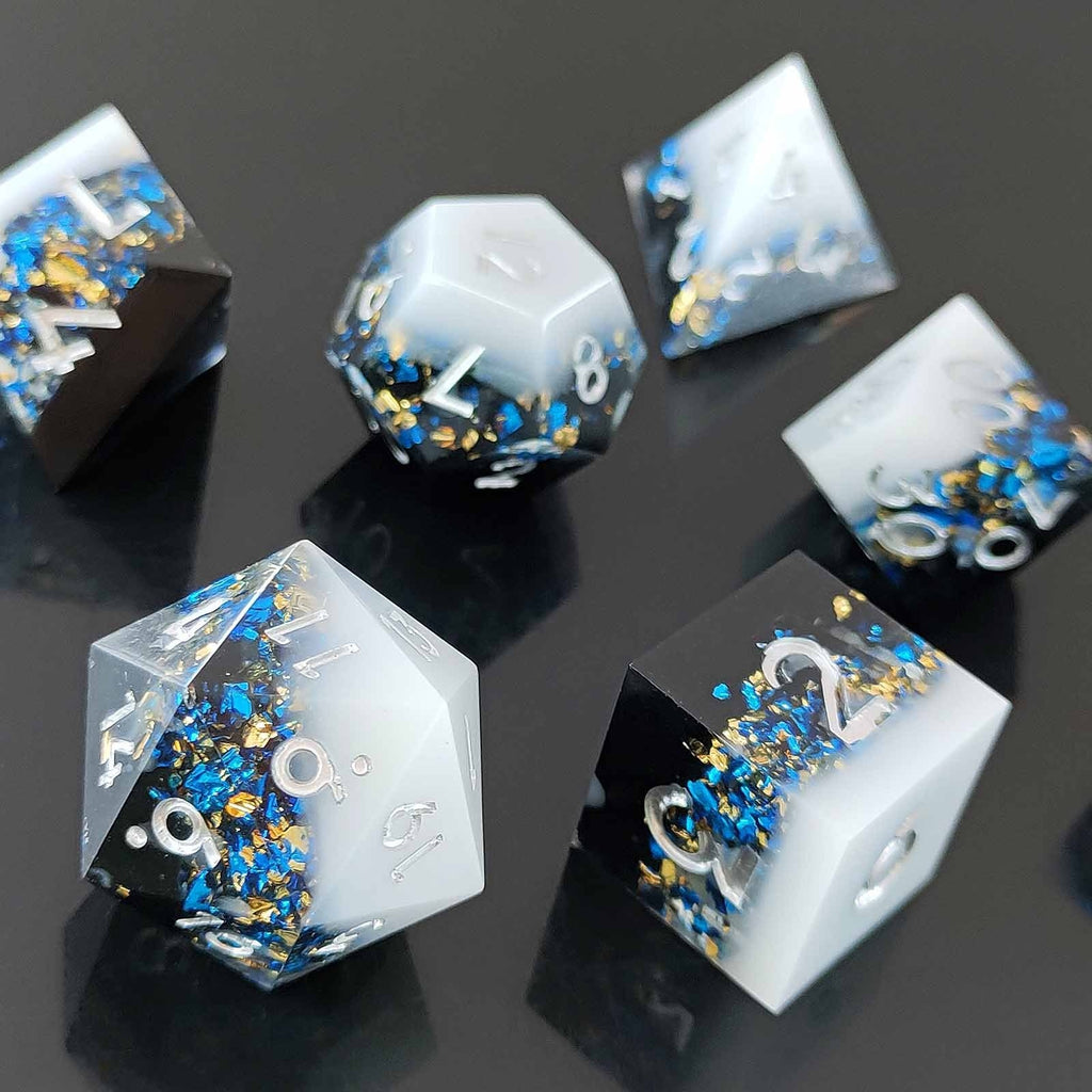 Set of  Liquid Core Resin dice with blue and gold embellishments on a reflective black surface