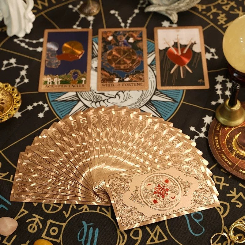 Gold tarot cards fanned out on a mystical table with tarot cards and decorative items.