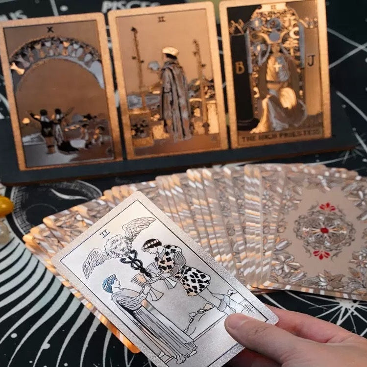 Hand holding a tarot card with other tarot cards and crystals on a black background