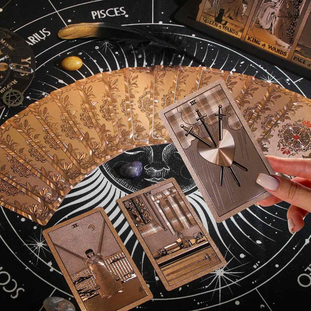 Collection of tarot cards on a tarot board with a hand holding one card.