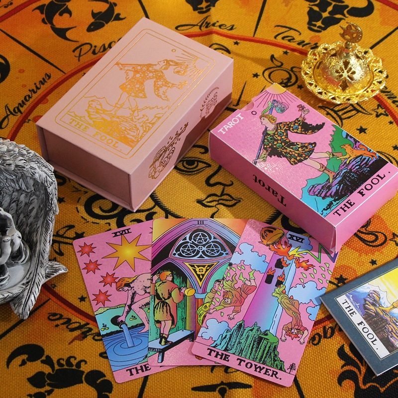 Pink tarot card deck with tarot cards and decorative items on a yellow background with astrological signs.