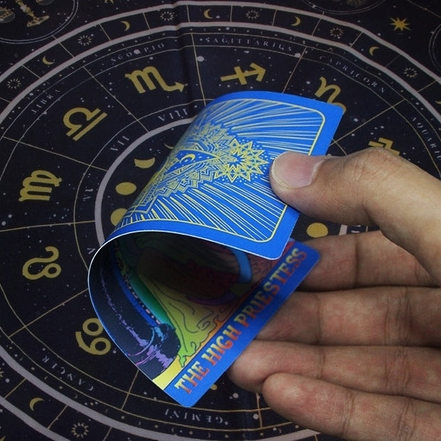 Hand holding a tarot card over a astrological chart