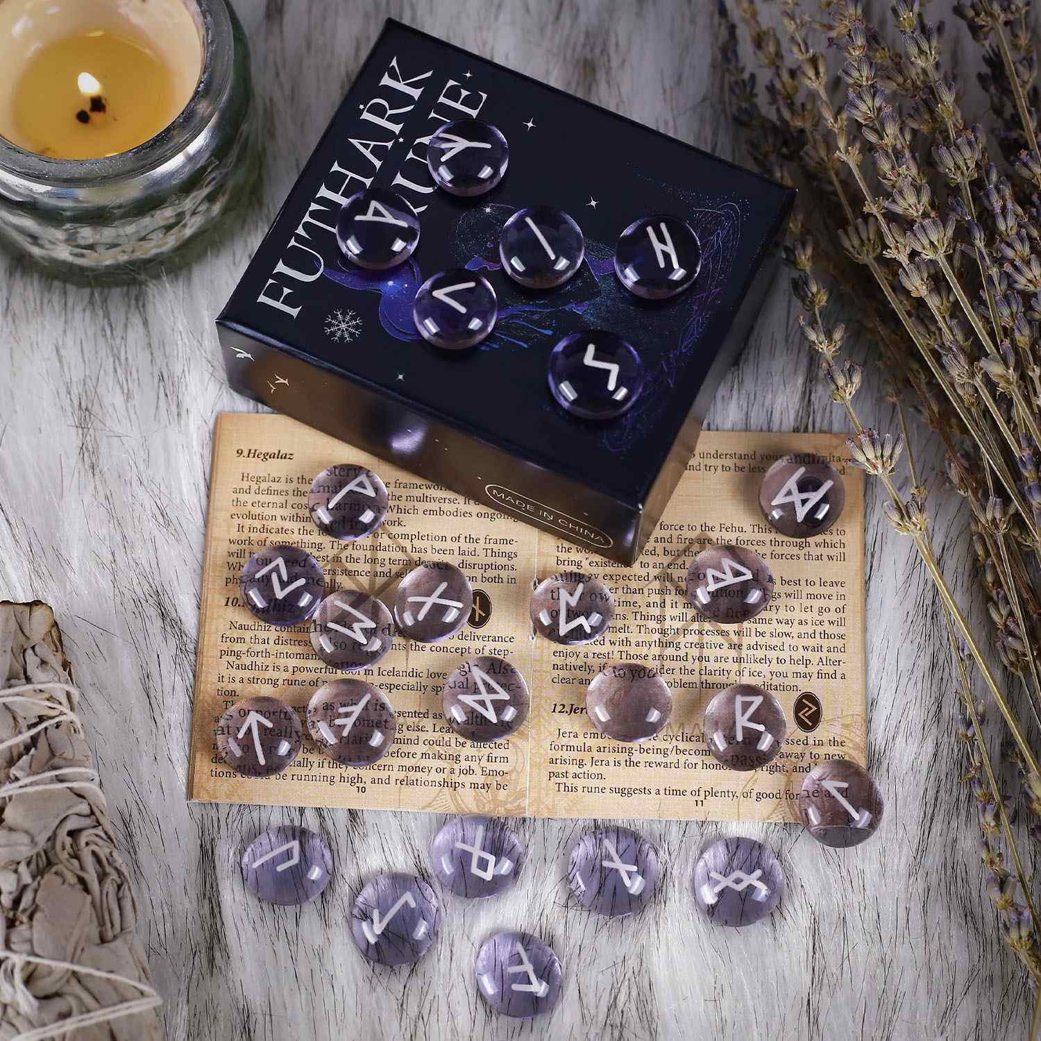 Set of rune stones with a box labeled 'Futhark Rune' on a wooden surface with a candle and dried herbs.