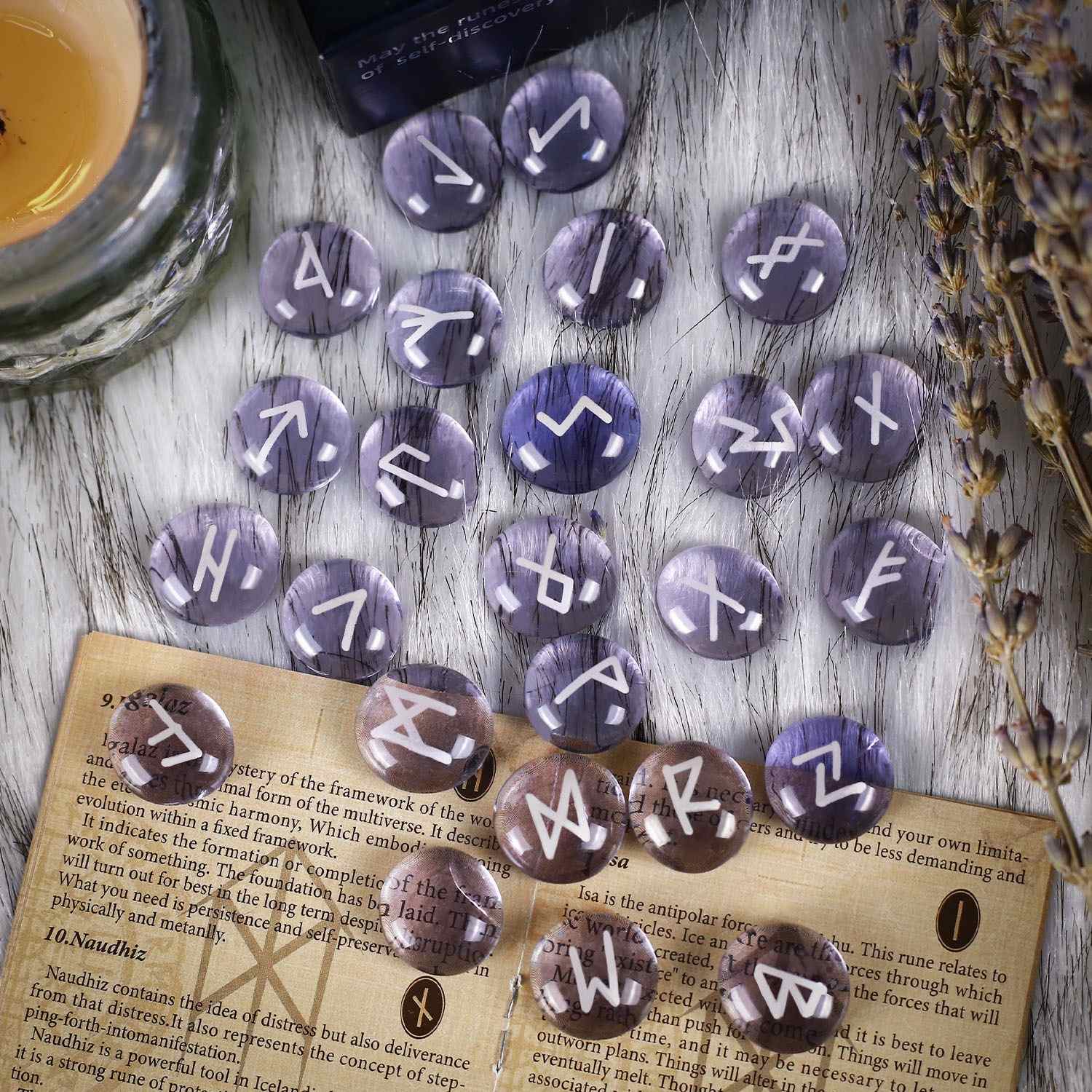 Purple rune stones on a wooden surface with a book and lavender.