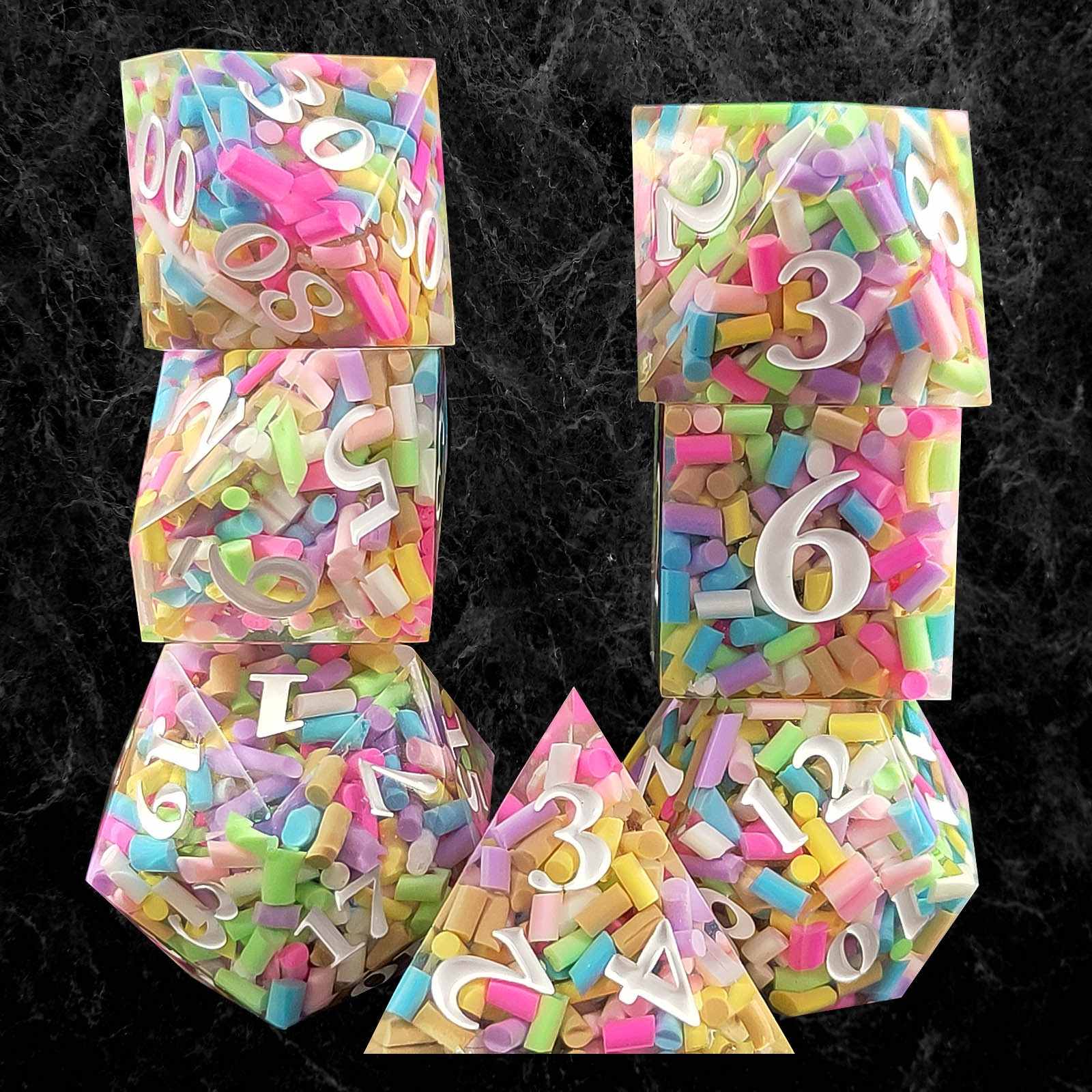 Set of colorful polyhedral resin dice with numbers and letters on a black background