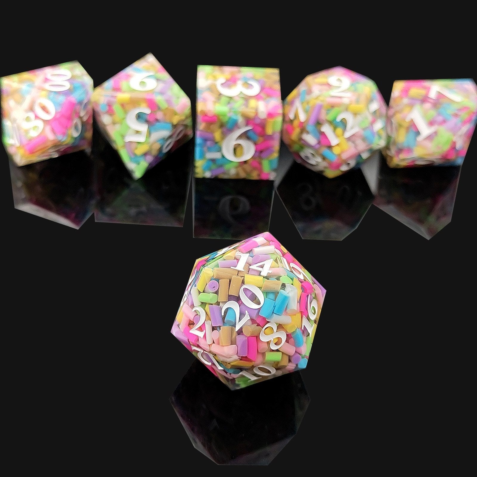 Set of colorful polyhedral resin dice with letter and number design on a black background