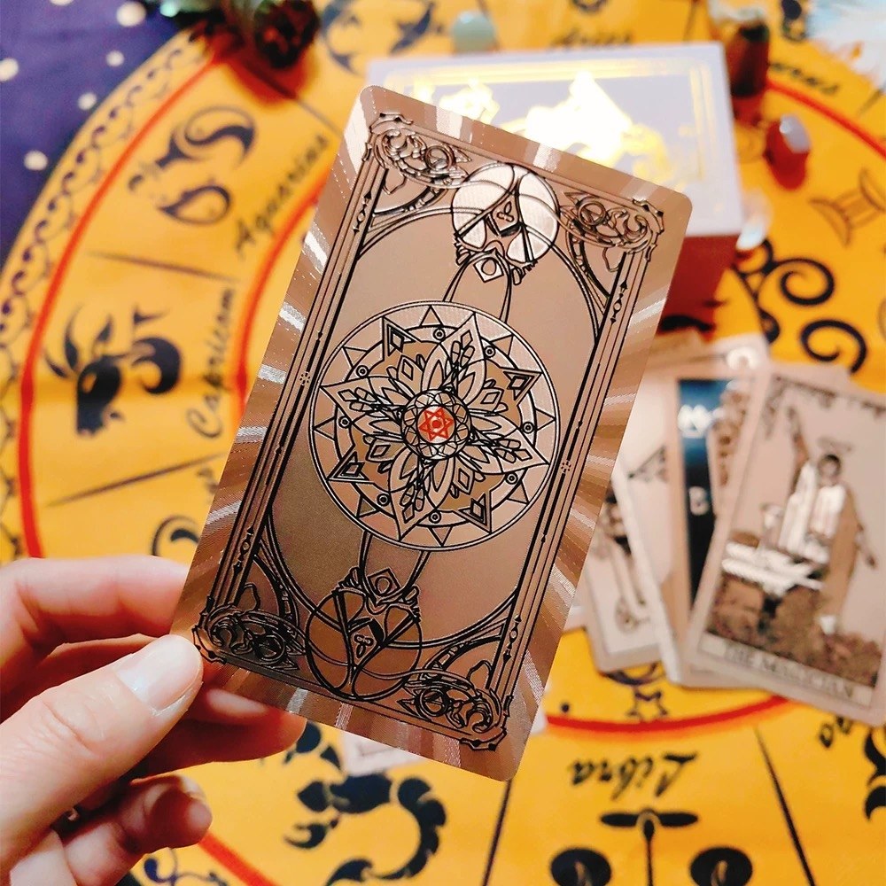 Person holding a Rose Gold Holographic tarot card over a colorful tarot card deck